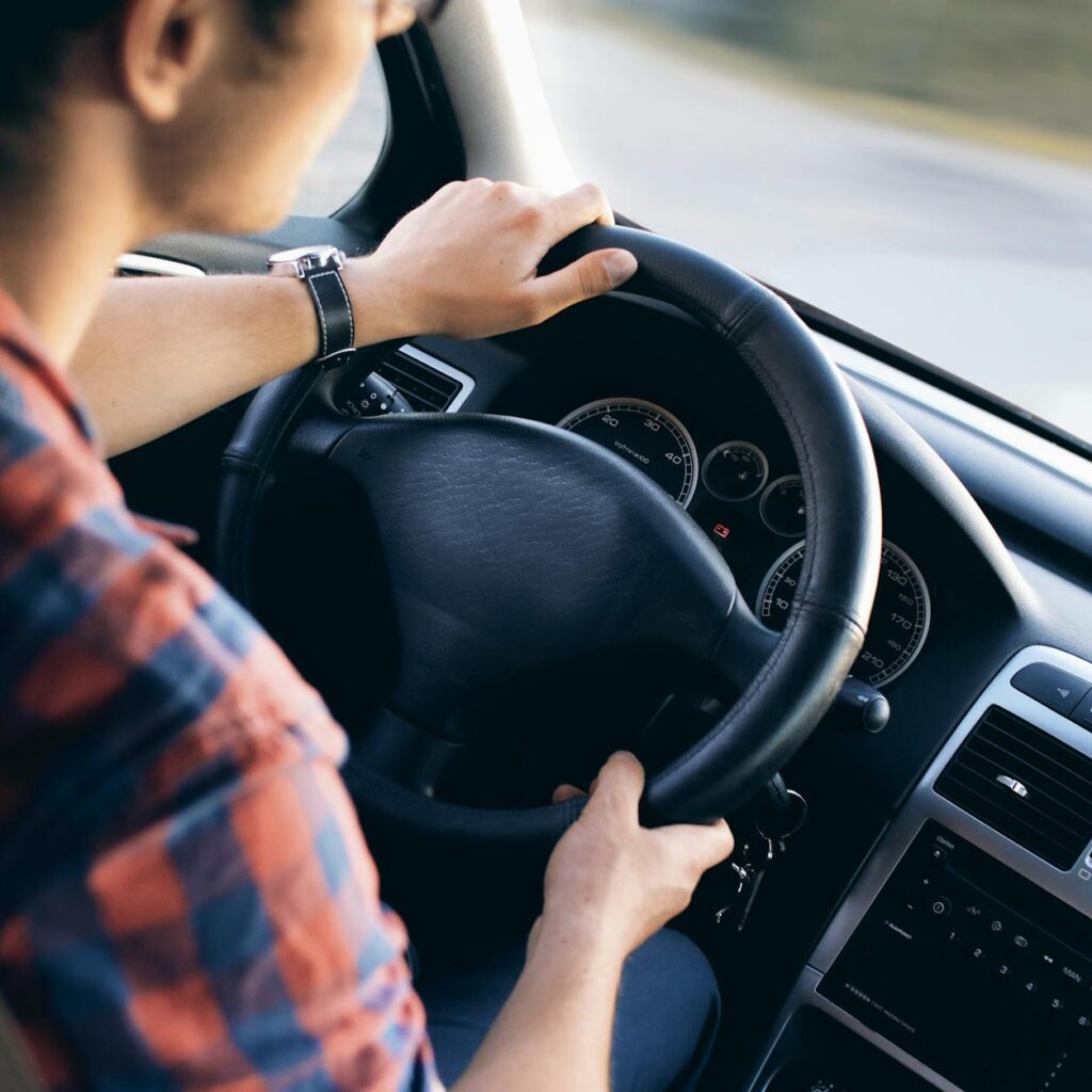 Close-up view of a man driving a modern car, showing dashboard and steering details.